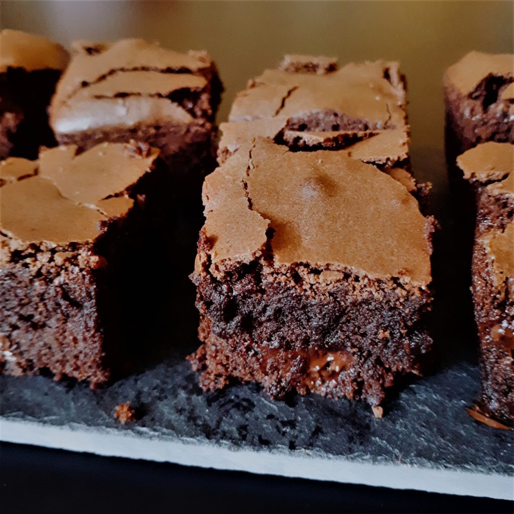 Detail zboku na stred brownies s roztopenou čokoládou položené na kamennej doske.