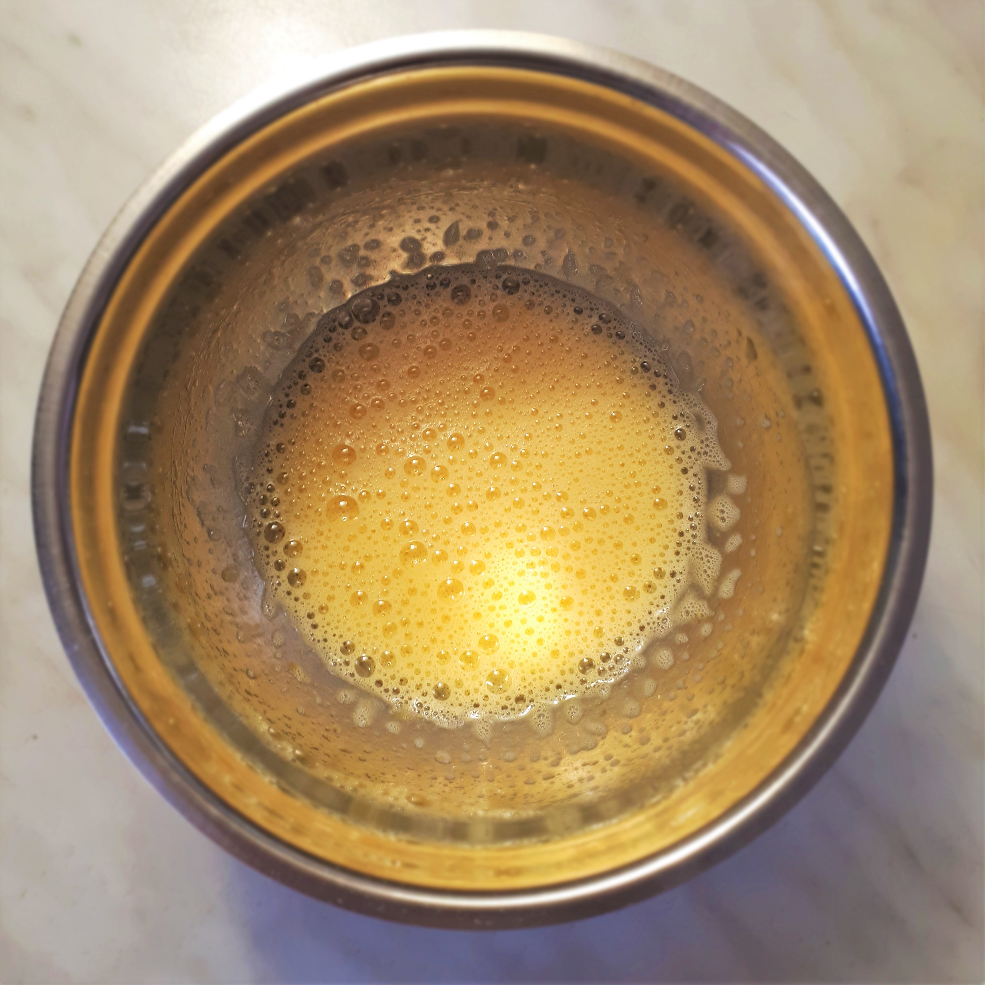 Vyšľahaný krém na lemon curd v antikorovej miske na mramorovom povrchu