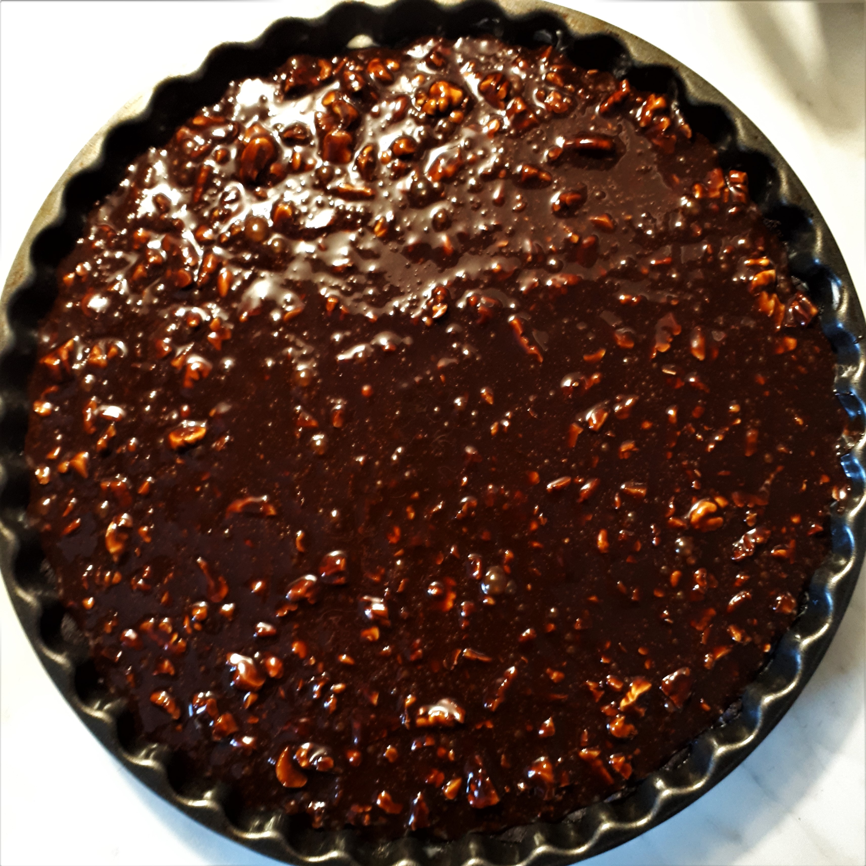 Forma na koláč s krehkým kakaovým cestom poliaty náplňou z čokolády a pekanových a vlašských orechov