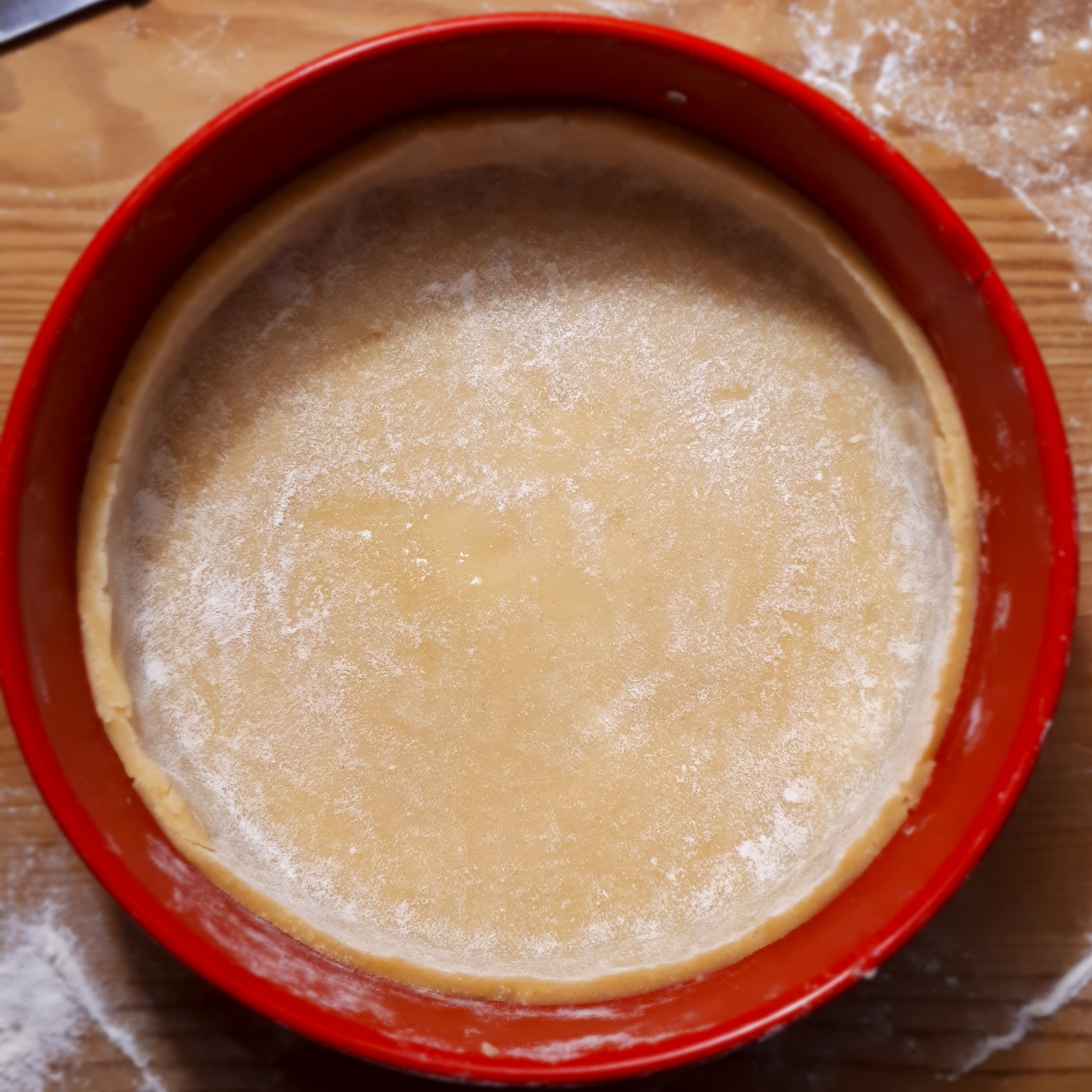 Cesto na tart v červenej tortovej forme na drevenom povrchu