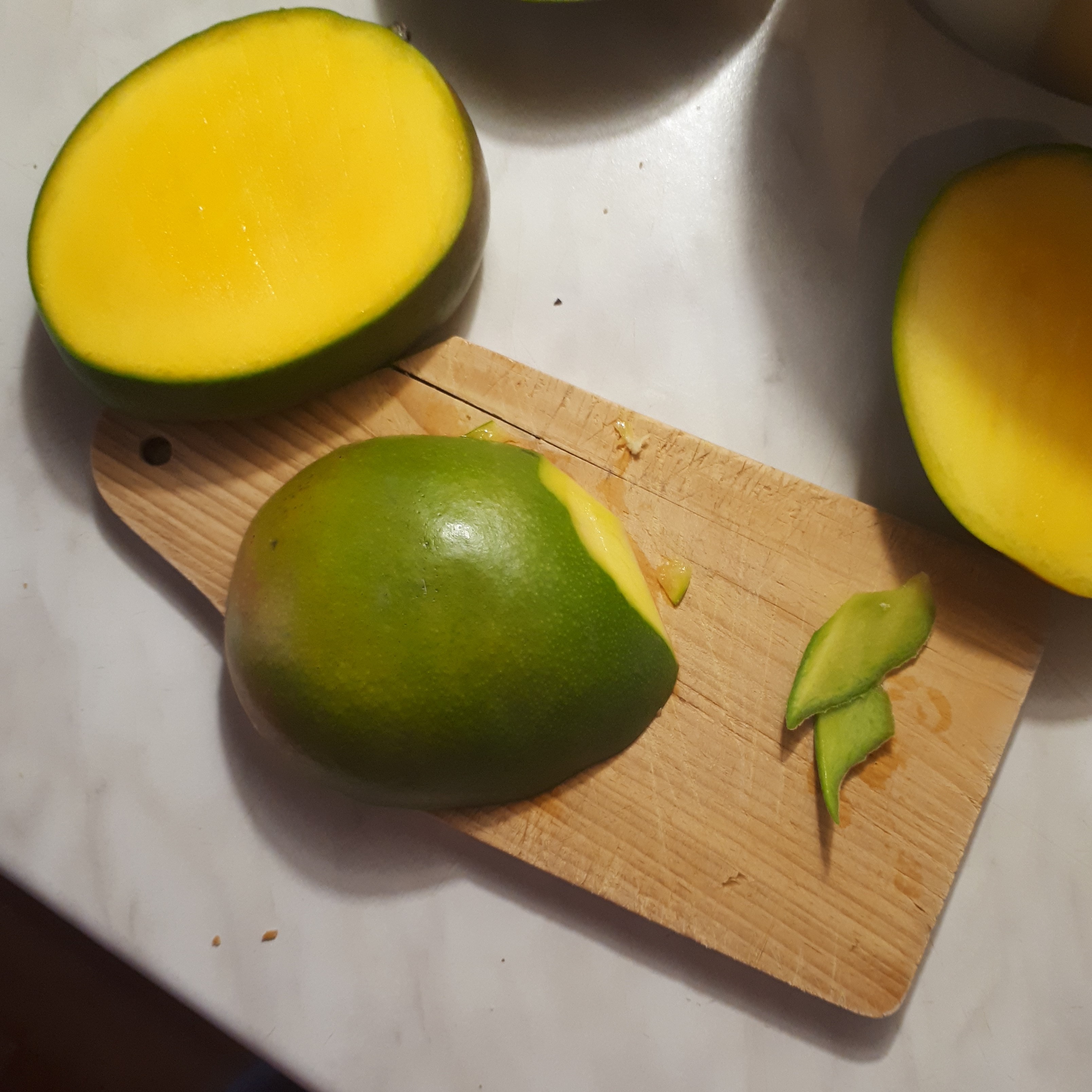 ROzpolené mango kúsok okrájaný na drevenej doske na mramorovom povrchu