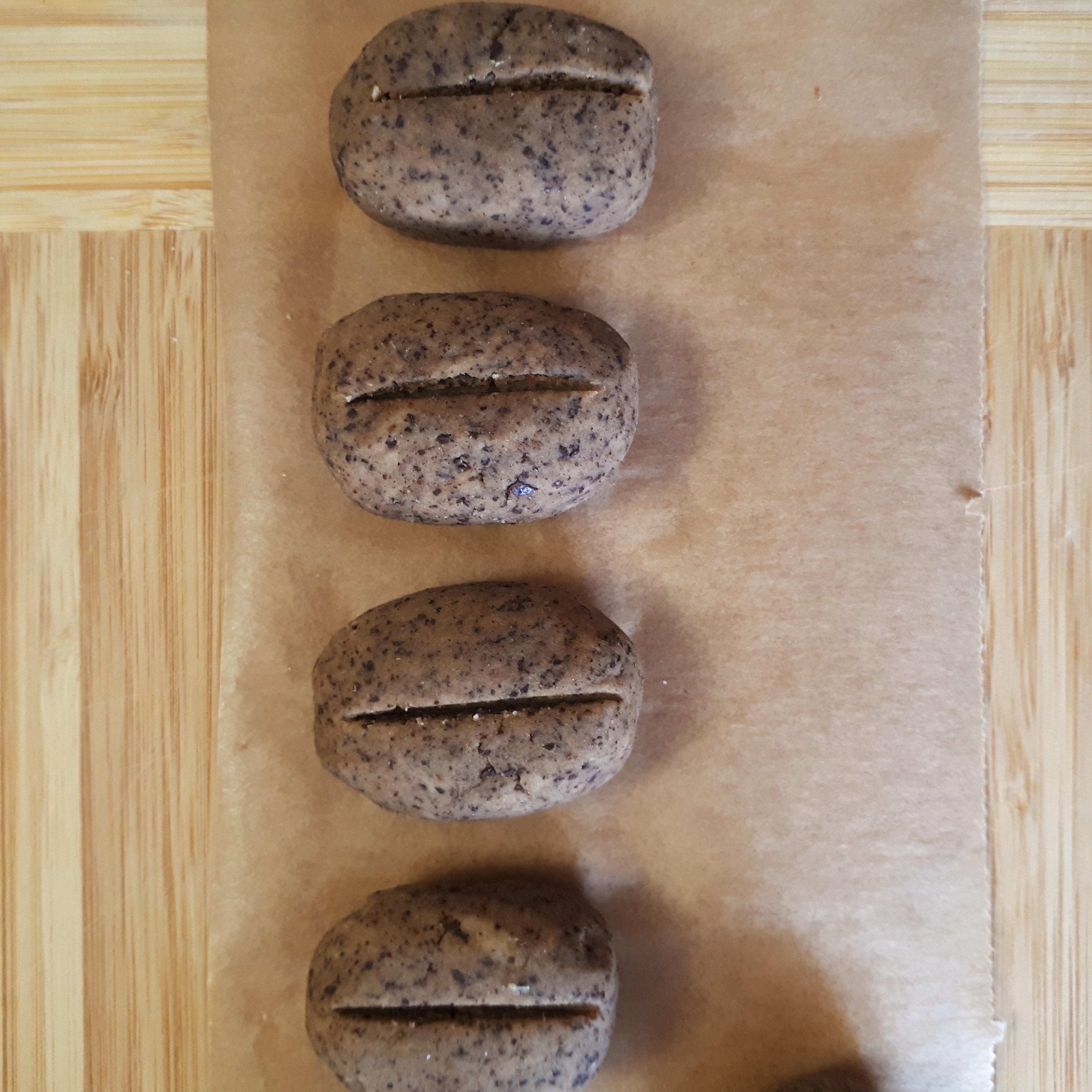 Štyri kávové zrná z gaštanového pyré na drevenej doske s papierom na pečenie