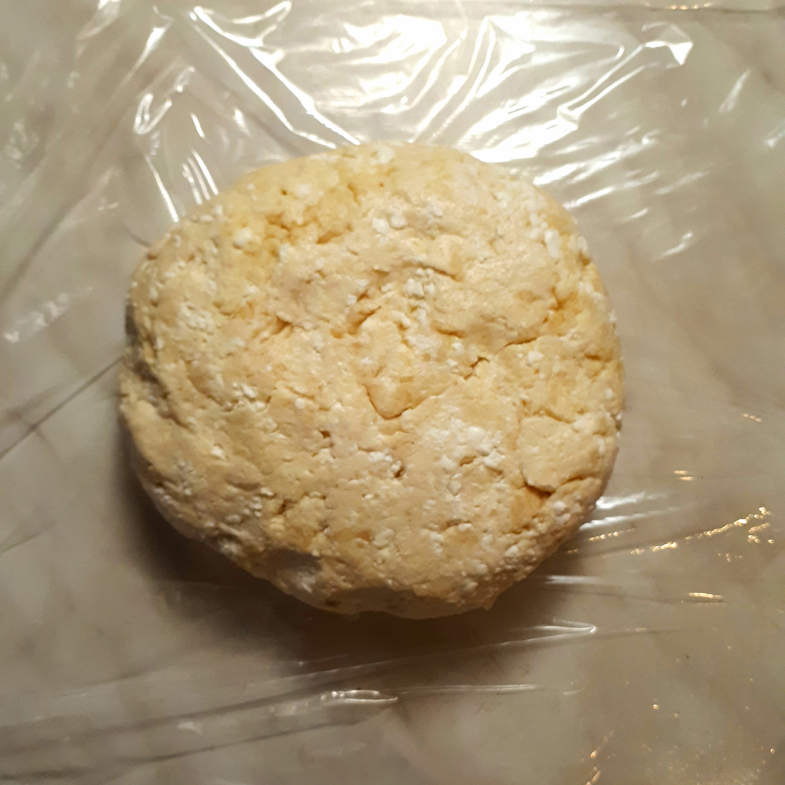 Vymiesené cesto z cottage cheese na potravinovej fólii na mramorovom povrchu