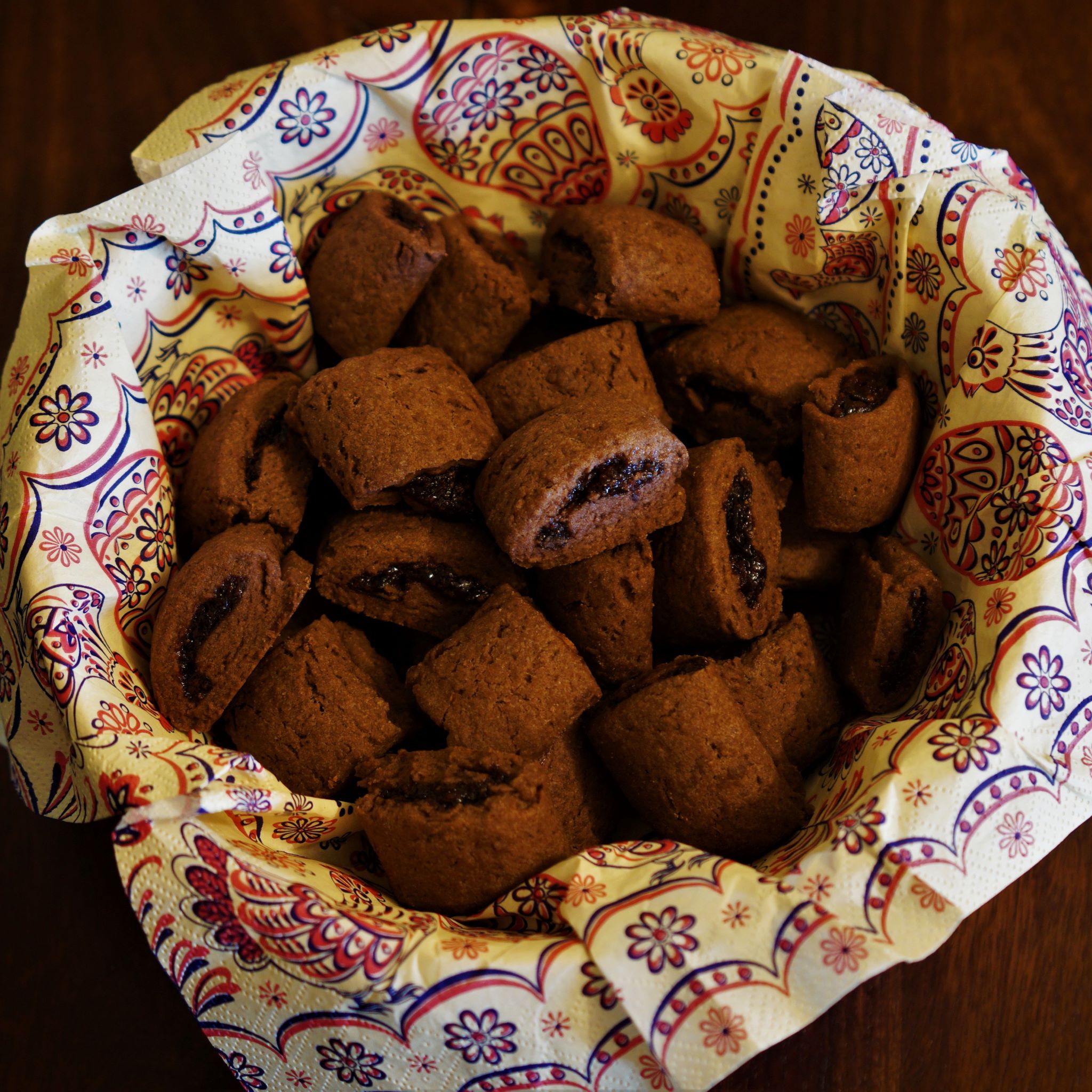 Kakaové sušienky plnené slivkovým lekvárom v miske vystlanej vzorovaným servítkom na tmavo hnedom drevenom stole