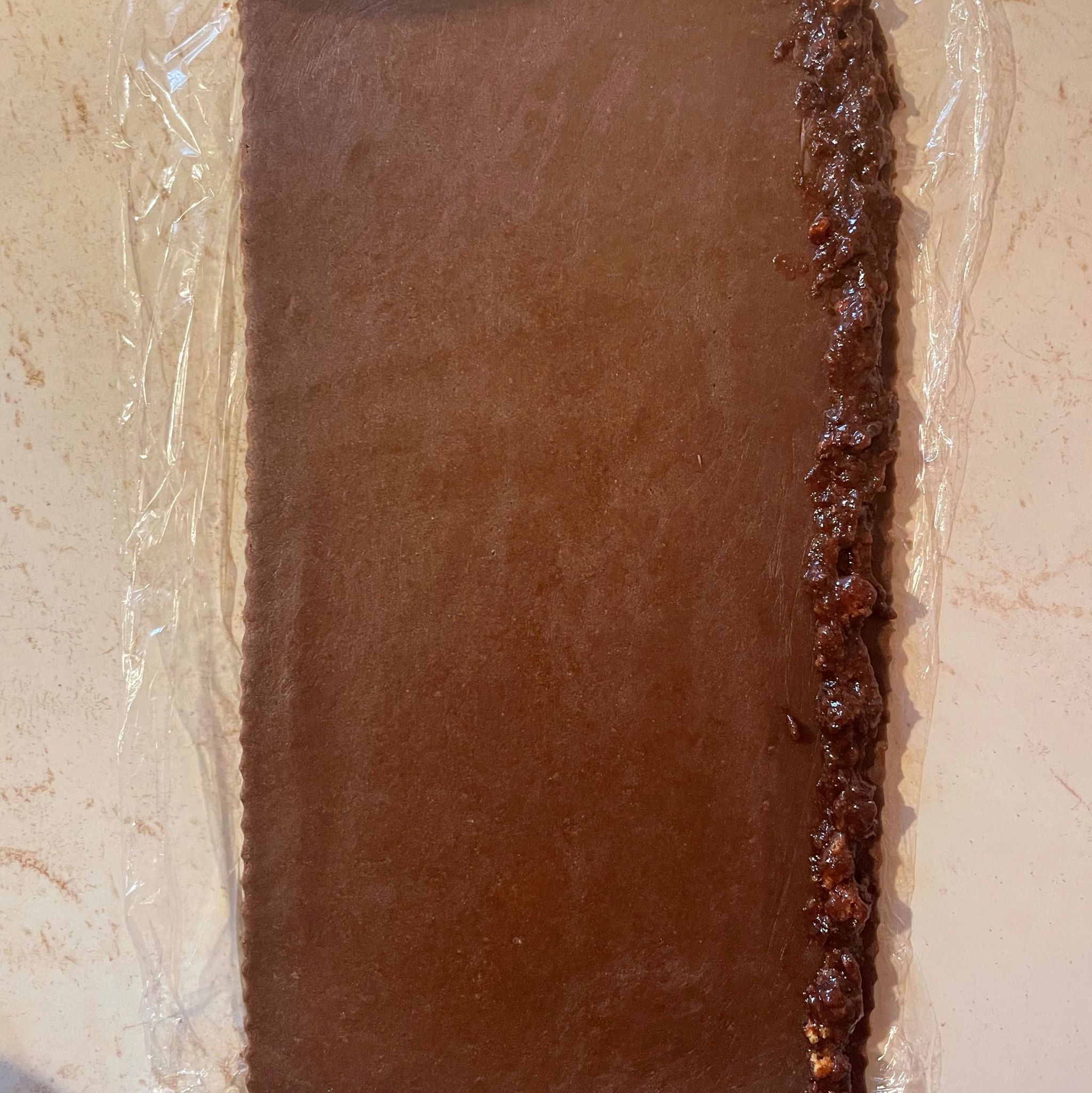 Obdĺžnik rozvaľkaného kakaového cesta na okraji náplň zo slivkového lekváru a perníku